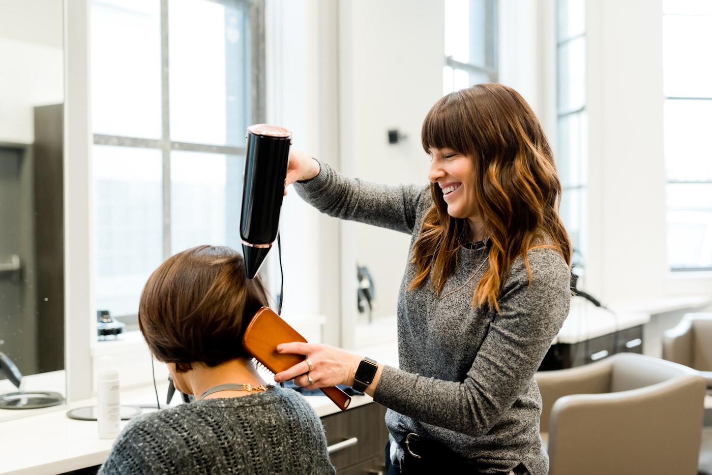 A stylist working colour through a client’s hair in the salon