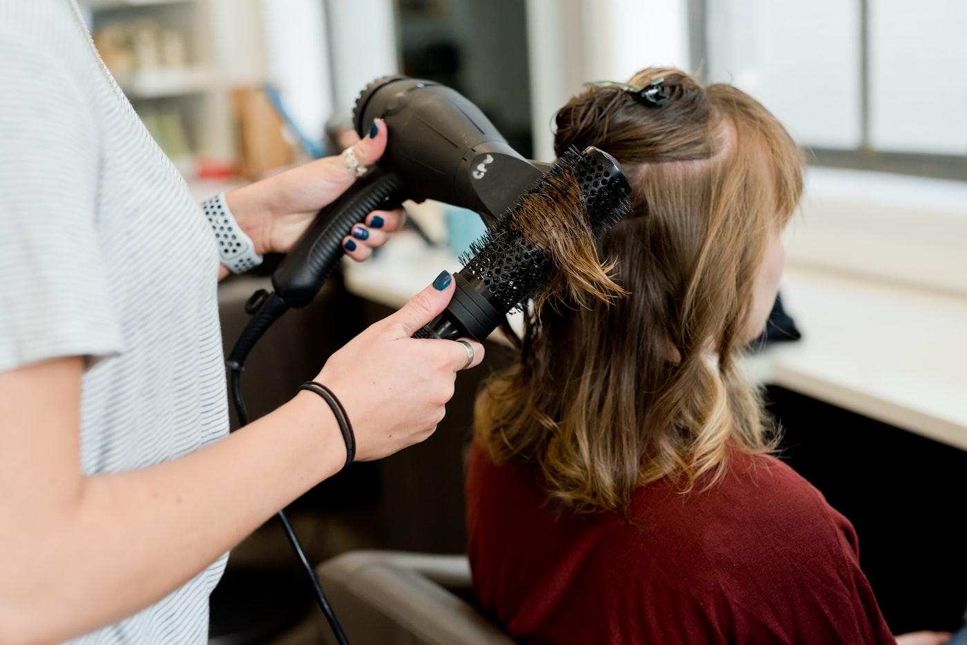 Long hair being smoothed out with a round brush and dryer